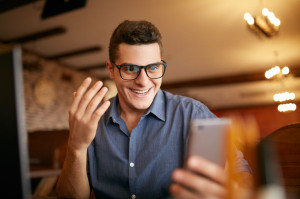 Surprised freelancer hipster man looks to smartphone and can not believe he won lottery prize or money in trading cryptocurrency. Pop-eyed successfull amazed businessman trader. Video call conference